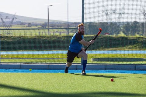 Male hockey player aiming at ball on field with intensity
