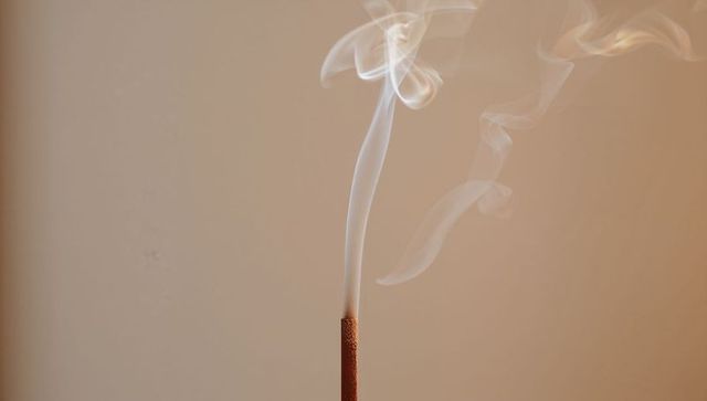 Minimalist incense stick releasing graceful smoke in beige monochrome for relaxation