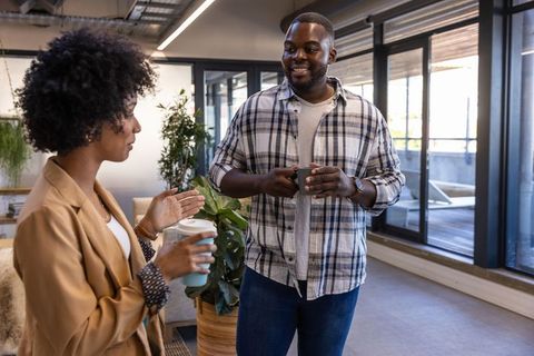 Diverse colleagues engaging in workplace discussion with drinks