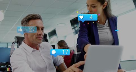 Coworkers analyzing social media engagement on laptop in modern open office workspace