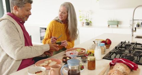 Senior couple enjoying avocado toast preparation in cozy kitchen