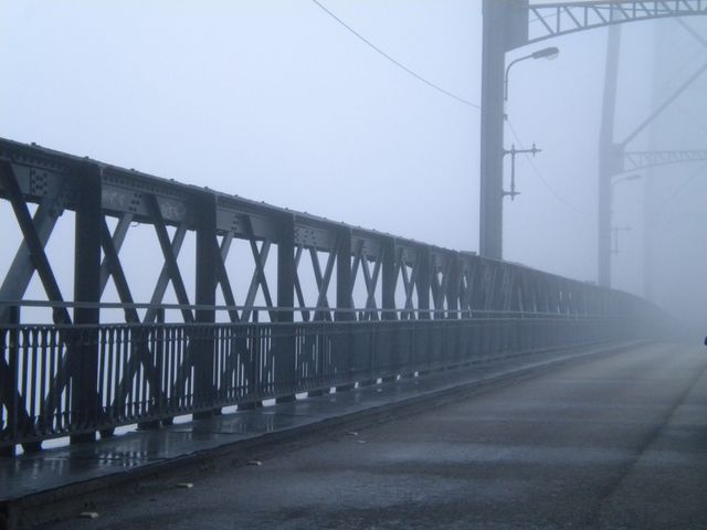 This image of an empty bridge engulfed in thick fog offers a moody and mysterious atmosphere. It captures the stillness and tranquility of a foggy morning in an industrial setting, making it perfect for use in themes related to transportation, urban life, mystery, and atmospheric settings. Ideal for blog posts, articles, backgrounds, and presentations needing a serene, contemplative, or slightly eerie visual.