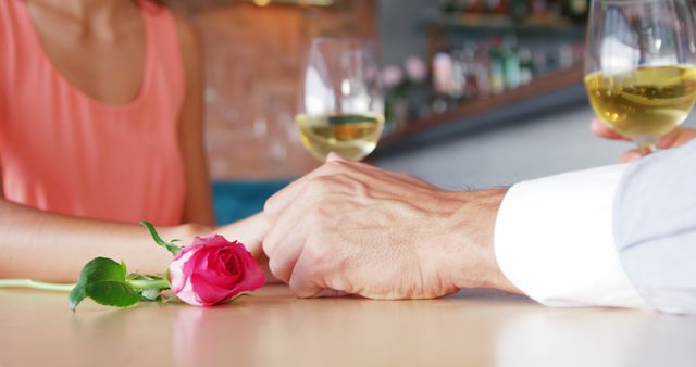 Mid-section of couple holding hands at restaurant table