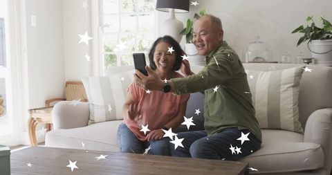 Mature couple taking selfie on sunlit sofa with star filter for social sharing