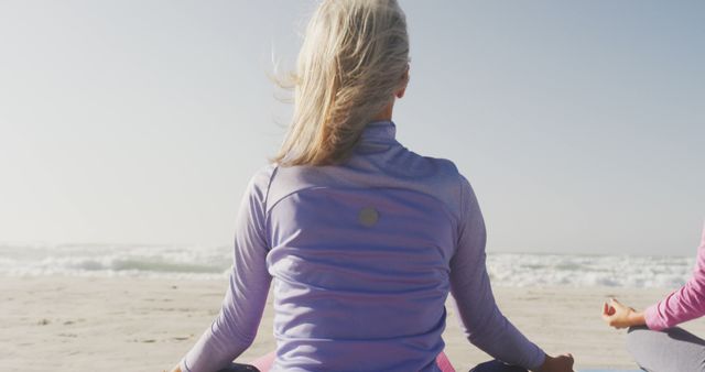Senior diverse women wearing sports clothes doing yoga and meditating at beach - Download Free Stock Photos Pikwizard.com