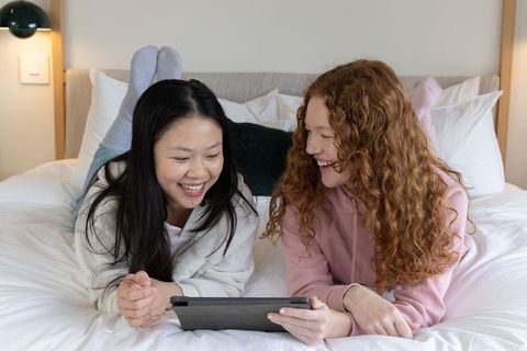 Two young women using tablet for spanish-english translation and online learning