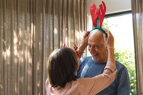 Senior couple playfully enjoys reindeer antler headbands in cozy living room