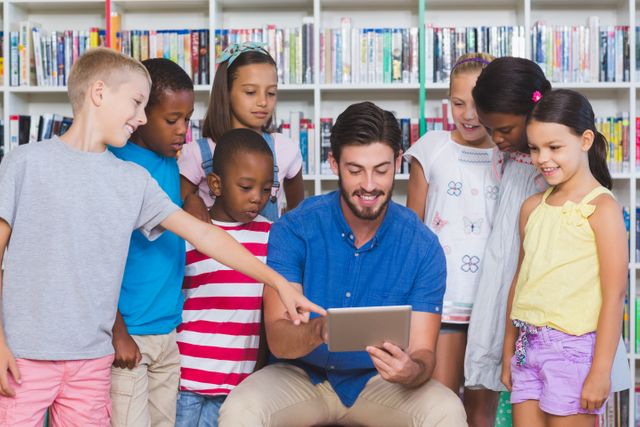 Teacher teaching kids on digital tablet in library at elementary school