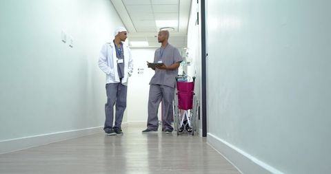 African american medical team discussing patient care in hospital corridor with wheelchair