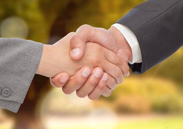 Digital composite image of business executives shaking hands against blurr background