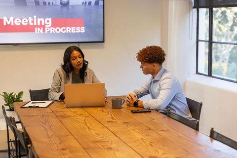 Diverse professionals collaborating over laptop and documents in modern conference room