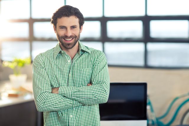 Portrait of smiling business executive standing with arms crossed in office