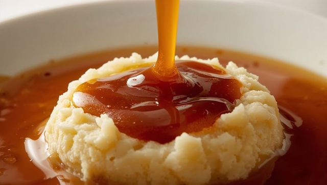 Rich brown gravy pouring onto creamy mashed potatoes