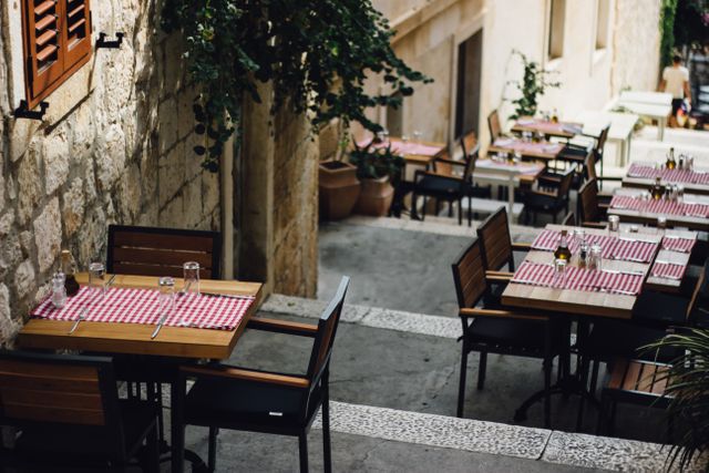 Empty Outdoor Cafe with Red Checkered Tablecloths on Cobbled Street - Download Free Stock Photos Pikwizard.com