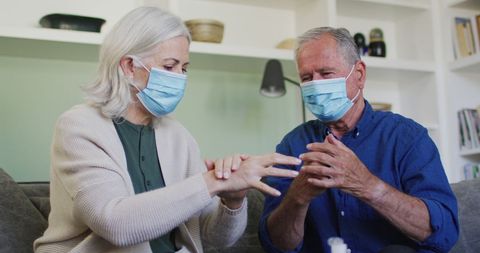 Senior Couple Sanitizing Hands for COVID-19 Precaution at Home