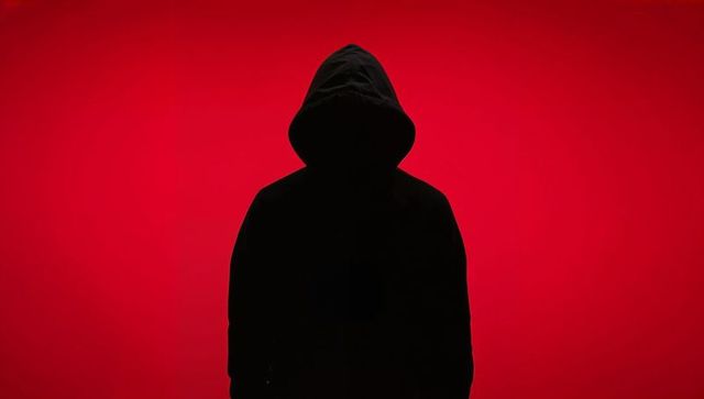 Hooded figure silhouette against red background