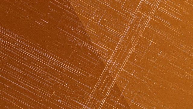 Abstract etched orange metallic surface with linear streaks
