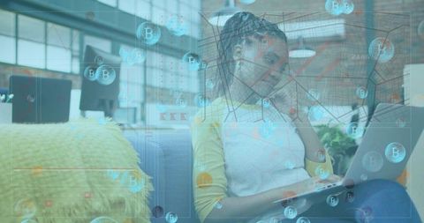 Working woman viewing Bitcoin analytics on laptop in coworking lounge with yellow top