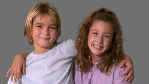 Smiling Siblings Embracing in Grey Background