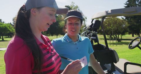Women Golfers Enjoying Game and Recording Scores on a Sunny Day