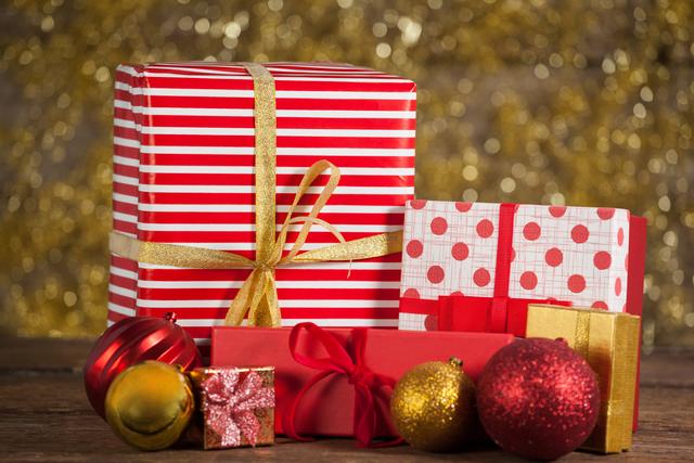 Festive wrapped gifts and baubles on a wooden table, perfect for holiday-themed promotions, greeting cards, and festive advertisements. The red and gold color scheme adds a warm, celebratory feel, ideal for Christmas marketing materials and seasonal social media posts.