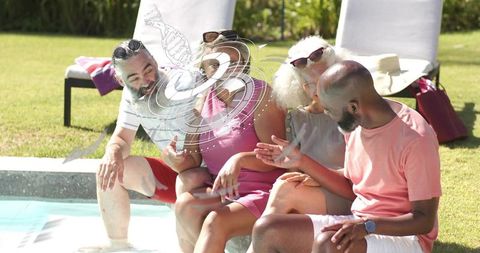 Friends chatting poolside dipping feet in pool relaxing on sunny backyard afternoon