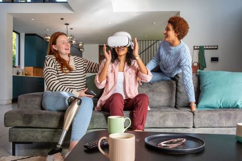 Diverse women socializing with vr headset in living room