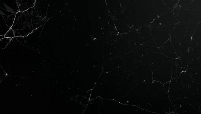 Dark cracked glass panel with hairline branching fissures and radial fracture texture