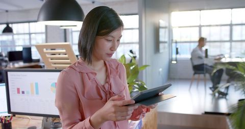 Asian Businesswoman Engaged With Tablet in Casual Office Environment - Download Free Stock Images Pikwizard.com
