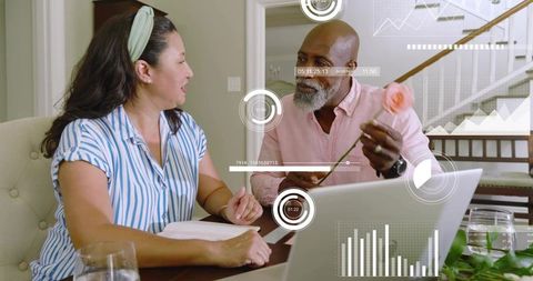 Mature couple reviewing home finances and chart analytics on laptop while sharing rose