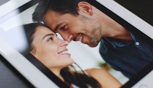 Couple leaning nose-to-nose on tablet, smiling in intimate digital portrait