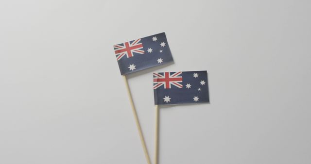 Two small Australia flags on sticks are photographed against a clean white background. The flags feature the Union Jack and the Commonwealth Star, representing national pride. This stock photo is suitable for use in content related to Australian national holidays, patriotism, international events, and educational materials about Australia.