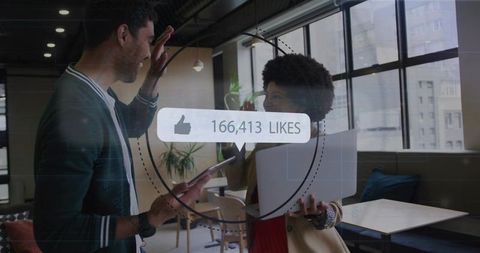 High-fiving coworkers celebrating social media success with digital likes overlay in modern office