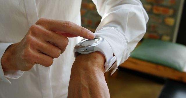 Focused close-up of a person using a smartwatch with a white strap, interacting with its features. Ideal for illustrating concepts of modern technology, wearable gadgets, personalization, lifestyle, and health tracking. Useful for websites, articles, or advertisements related to technology, fitness, smart devices, and innovative gadgets.