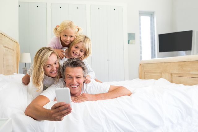 Happy family taking a selfie on mobile phone in the bed room at home