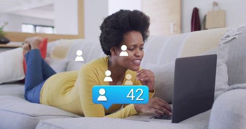 Lying woman typing laptop on sofa showing follower notification badge 42 for remote work networking