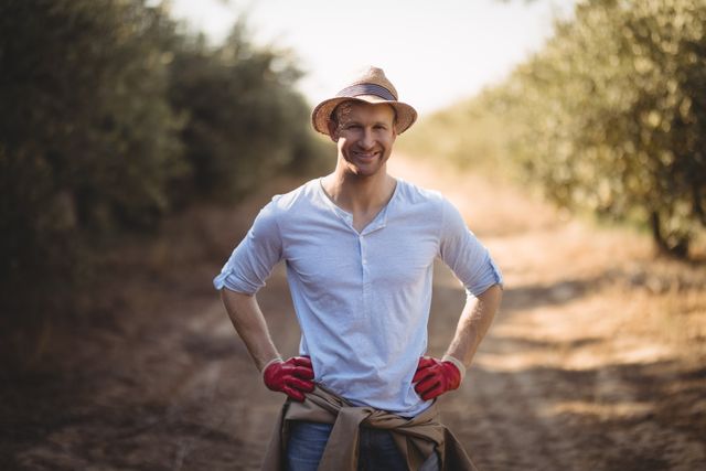 Portrait of smiling young man standing on dirt road at farm