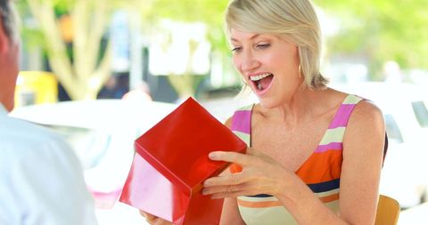 Joyful woman receiving gift in outdoor cafe