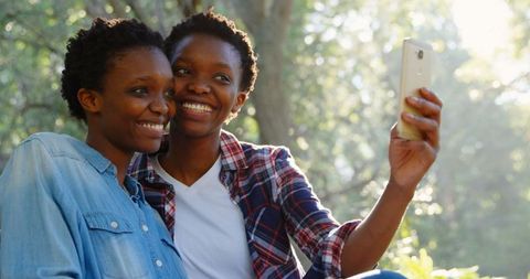 Smiling Twin Sisters Taking Selfie in Sunlit Park - Download Free Stock Images Pikwizard.com