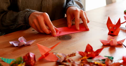 Hands Creating Colorful Origami at Home on Wooden Table