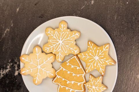 Holiday snowflake and christmas tree sugar cookies resting on white plate flatlay
