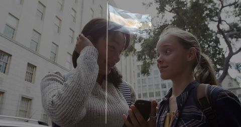 Teen Students Chatting on Urban Sidewalk Checking Phone with Argentina Flag Overlay