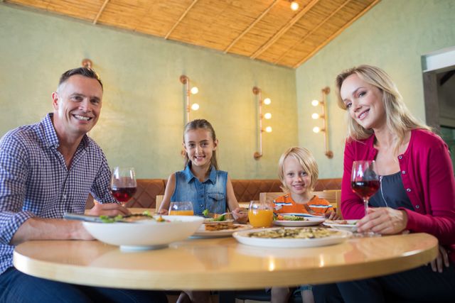 Family sitting together at a restaurant table, smiling and enjoying their meal, ideal for concepts related to family bonding, dining out, and mealtime happiness. Suitable for restaurant promotions, family-oriented advertisements, and articles on family life and dining experiences.