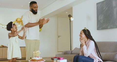 Family Celebrating Mother's Birthday At Home With Cake and Gifts