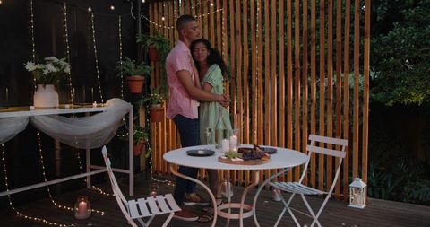Romantic couple embracing on patio with candlelit dinner