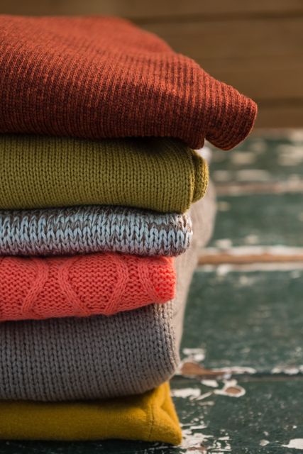 Close up of colorful stack of sweaters on wooden table