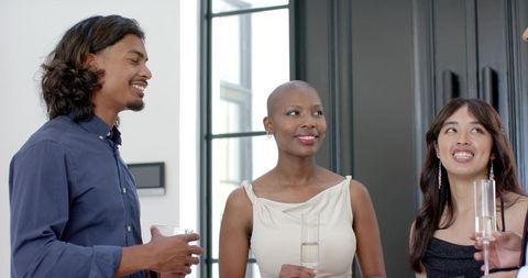 Smiling group holding champagne flutes in bright contemporary loft at cocktail gathering