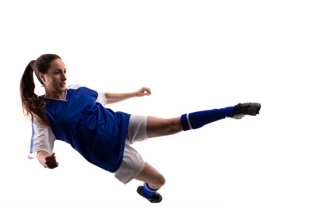 Full length of young female caucasian soccer athlete kicking mid-air against white background. unaltered, sport, competition and game concept.