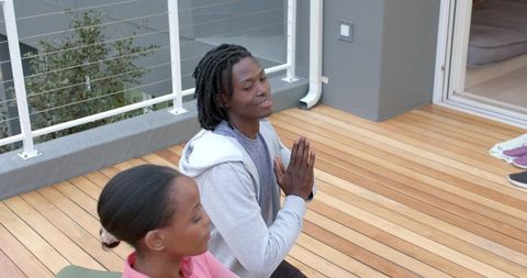 African american friends meditating on wooden deck practicing yoga and mindfulness