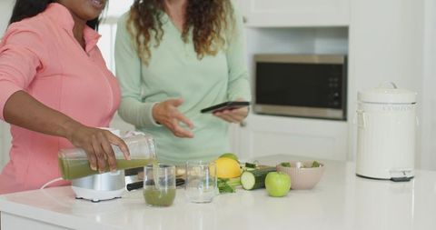 Diverse Women Making Healthy Green Smoothie in Modern Kitchen